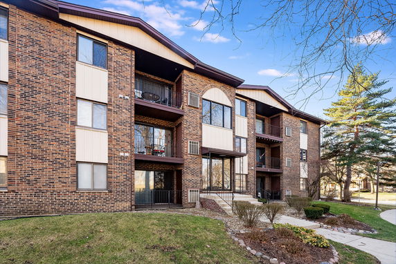 Front view of a multi-story brick apartment building with balconies.