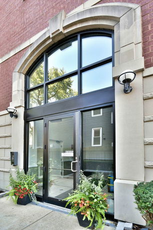 Front view of a building entrance with a large arched window and glass doors.