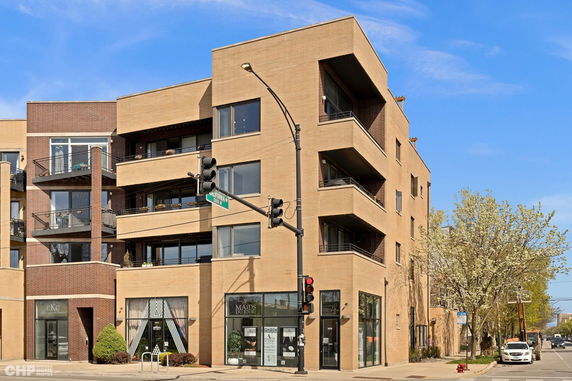 Front view of a modern multi-story building with balconies and large windows.