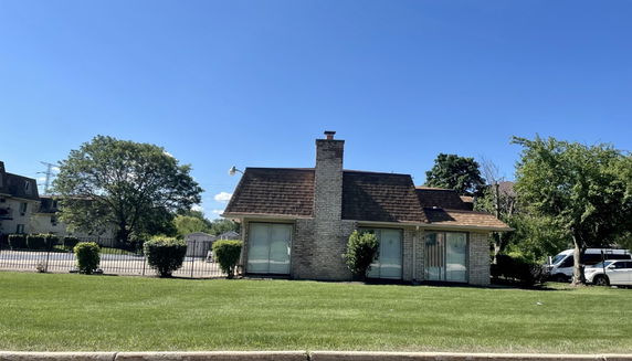 Front view of a house with a central chimney and large windows.