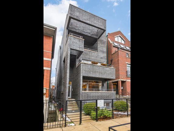 Front view of a three-story modern house with a dark brick facade.