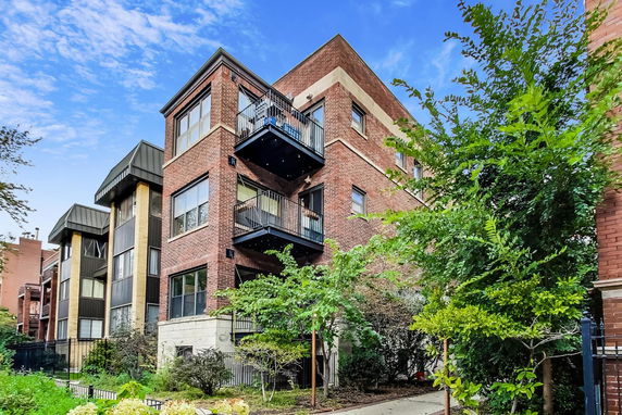 Front view of a multi-story brick residential building with balconies.