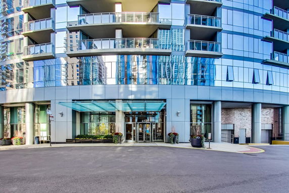 Front view of a modern multi-story building with glass facade and balconies.