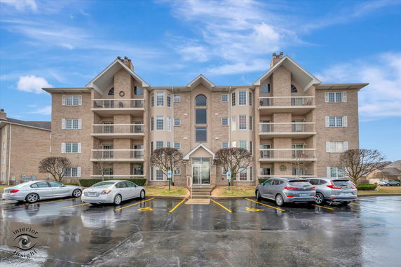 Front view of a multi-story brick apartment building with balconies.