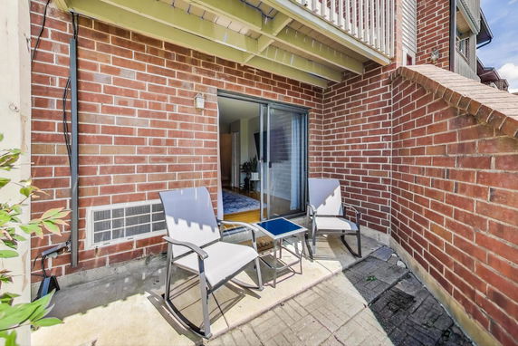 View of a brick patio area with sliding doors and two chairs.
