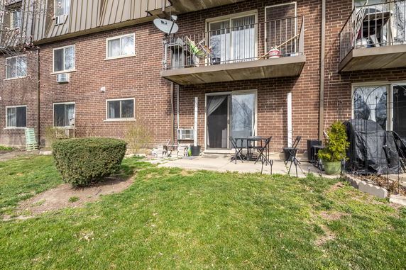 Front view of a brick building with balconies and a patio area.