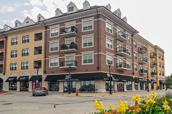 Front view of a multi-story brick building with balconies and ground-floor shops.