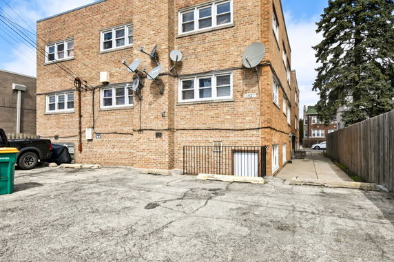Side view of a brick multi-story building with multiple satellite dishes attached.