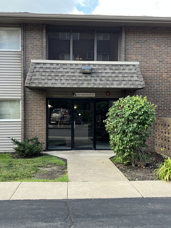 Front view of a two-story brick building entrance with a shingled awning.