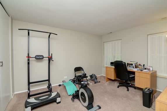 Interior view of a home gym and office space with exercise equipment and a desk.