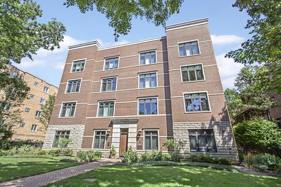 Front view of a multi-story apartment building with brick facade and multiple windows.