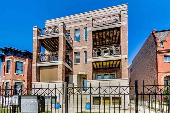 Front view of a three-story brick building with balconies.