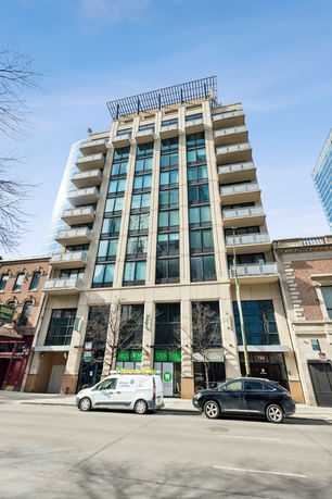 Front view of a multi-story building with glass windows and balconies.