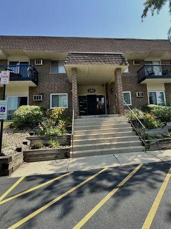 Front view of a brick apartment building with balconies and a central entrance.