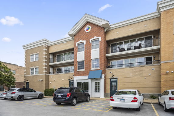 Front view of a multi-story building with brick facade and balconies.