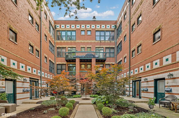 Front view of a multi-story brick apartment building with a central courtyard.