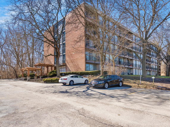 Front view of a multi-story residential building with parking area.