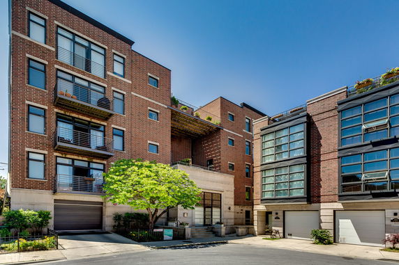 Front view of a multi-story brick residential building with large windows.