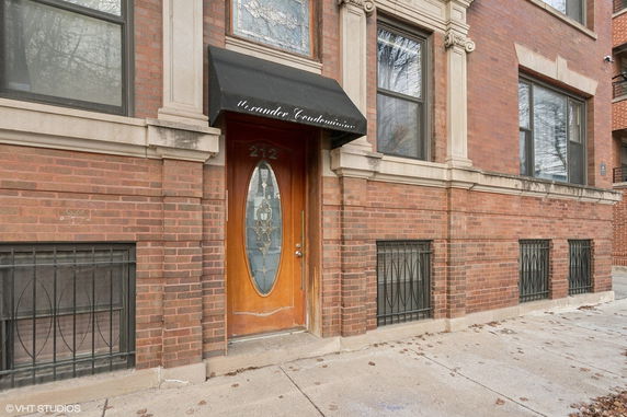 Front view of a brick building with a decorative wooden door and a black canopy.