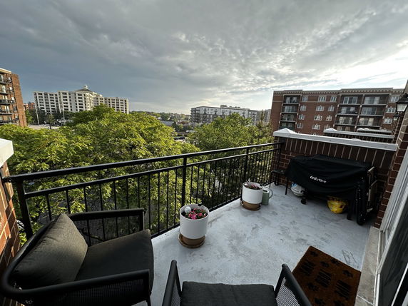 Balcony view overlooking buildings and trees in an urban area.