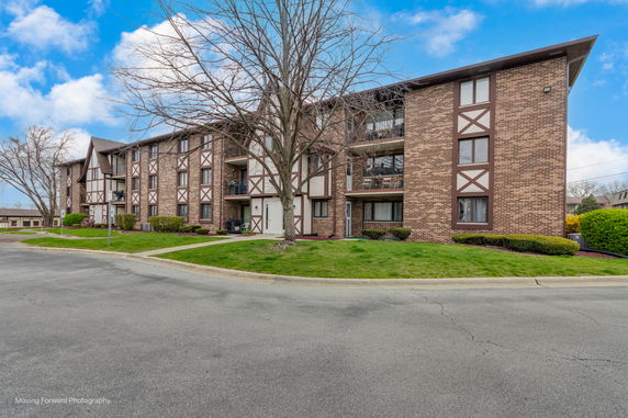 Front view of a multi-story apartment building with a brick facade and balconies.