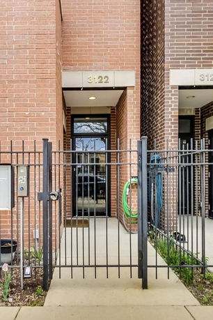 Front view of a brick-faced building entrance with a black metal gate.