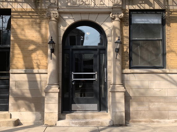 Front view of a building entrance with columns and lanterns.