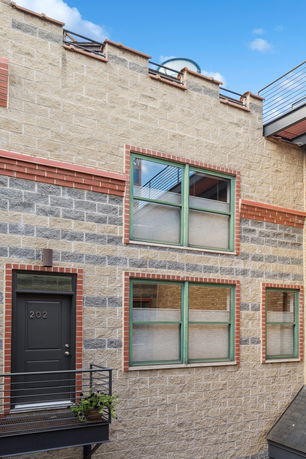 Exterior view of a brick building with green-framed windows and a door labeled 202.