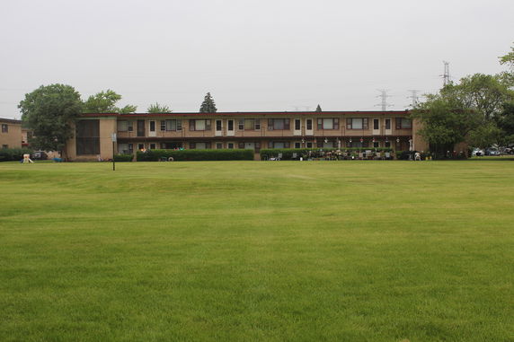 Front view of a two-story residential building with a large lawn in the foreground.