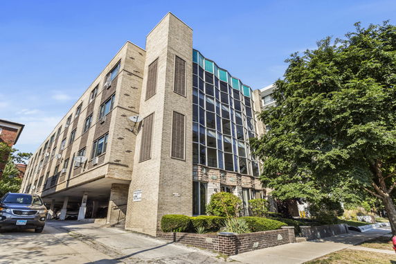 Front view of a multi-story building with large windows and brick exterior.