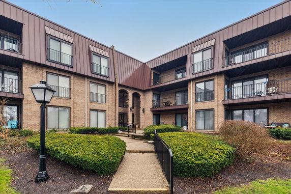 Front view of a multi-story apartment building with balconies and a central entrance.