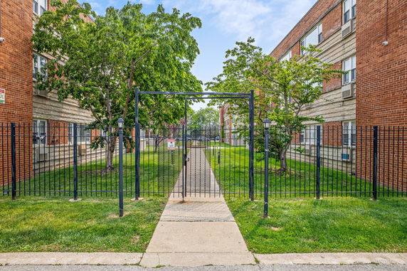 Front view of a multi-story brick building with a gated entrance.