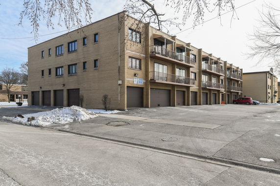 Front view of a three-story brick apartment building with balconies and garages.