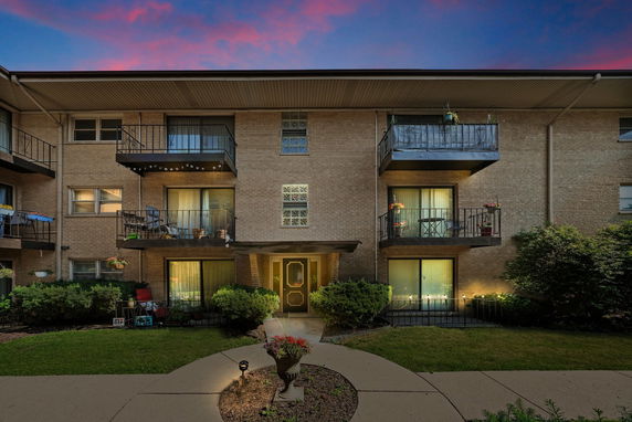 Front view of a three-story building with multiple balconies and a central entrance.