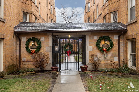 Front view of a brick building with festive wreaths and a gated entrance.