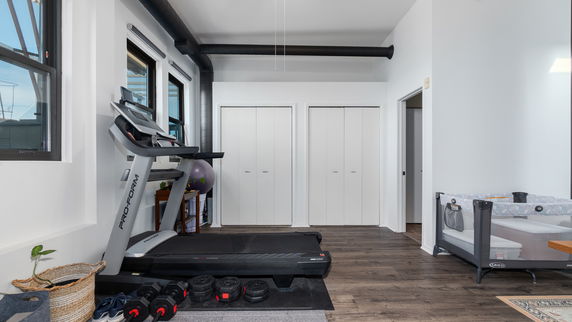 Indoor room with gym equipment including a treadmill and weights.