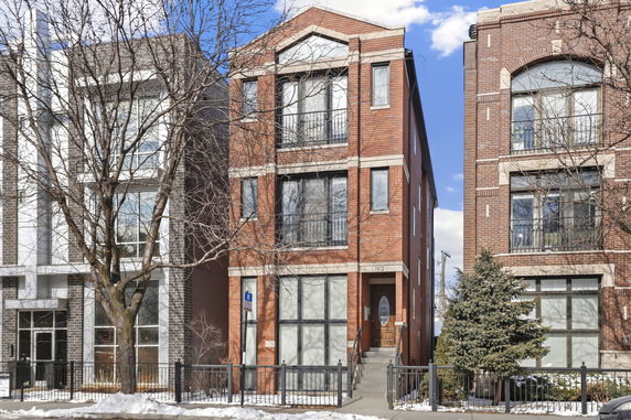 Front view of a multi-story brick building with large windows and a staircase leading to the entrance.