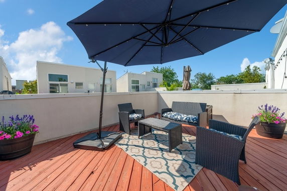 Rooftop patio with seating area, umbrella, and potted plants.