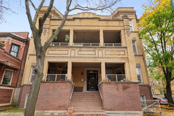 Front view of a multi-story brick building with a central entrance and balconies.