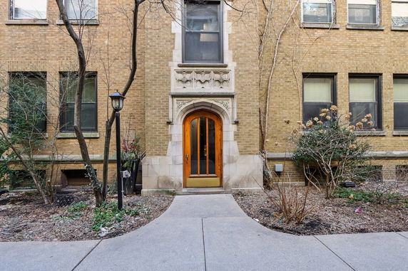 Front view of a brick building entrance with an arched wooden door.
