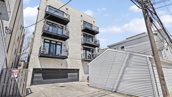 Front view of a multi-story building with balconies and a garage on the ground floor.