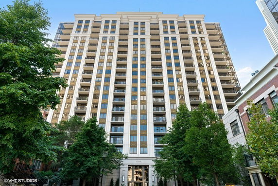 Front view of a tall residential building with multiple balconies.