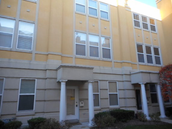 Front view of a multi-story building with several windows and pillars at the entrance.