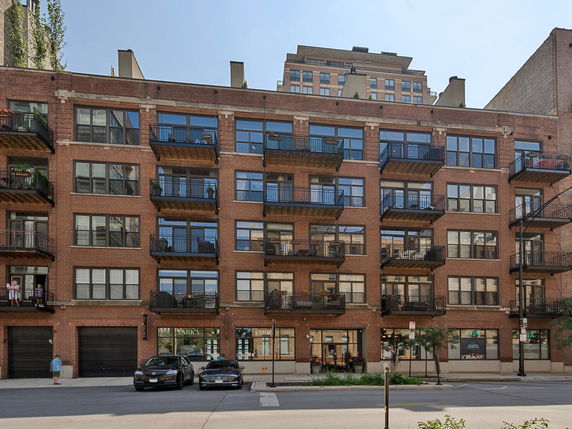 Front view of a multi-story brick apartment building with balconies.