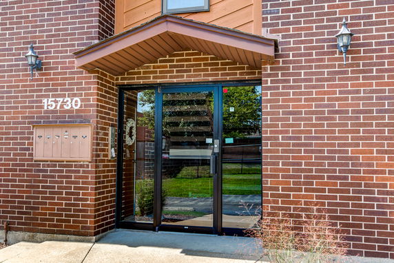 Front view of a brick building entrance with a canopy and glass doors.