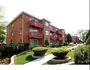 Front view of a multi-story brick apartment building with balconies.