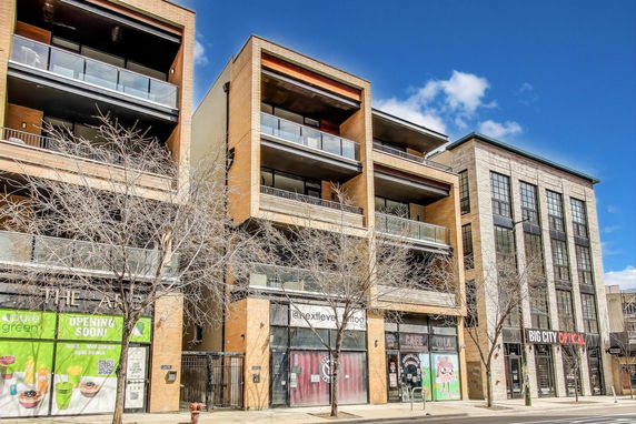 Front view of a multi-story commercial and residential building with glass balconies.