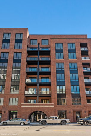 Front view of a multi-story brick apartment building with large windows and balconies.