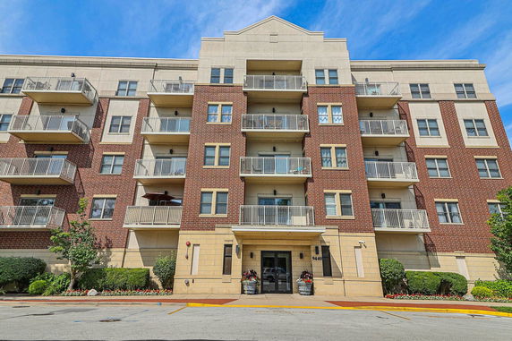 Front view of a multi-story brick apartment building with balconies.