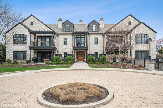 Front view of a large multi-story house with a stone facade and multiple gables.